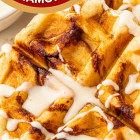 Cinnamon Roll Waffles on a a plate with cream cheese icing drizzled on top.