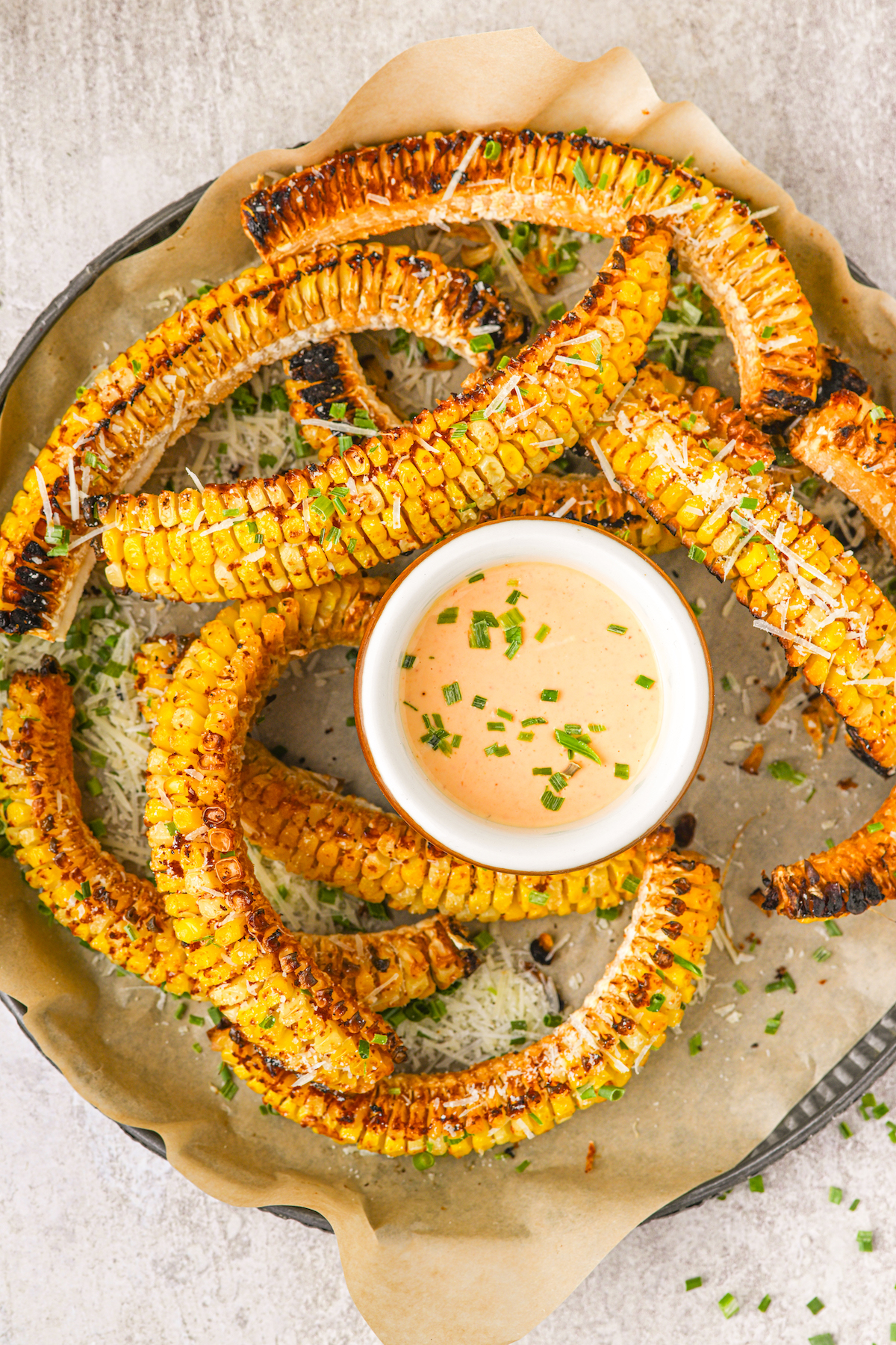Overhead shot of baked corn with creamy dipping sauce.