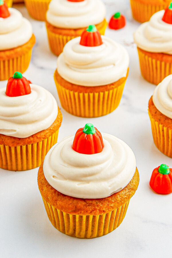 Frosted cupcakes decorated with small pumpkin-shaped candies.