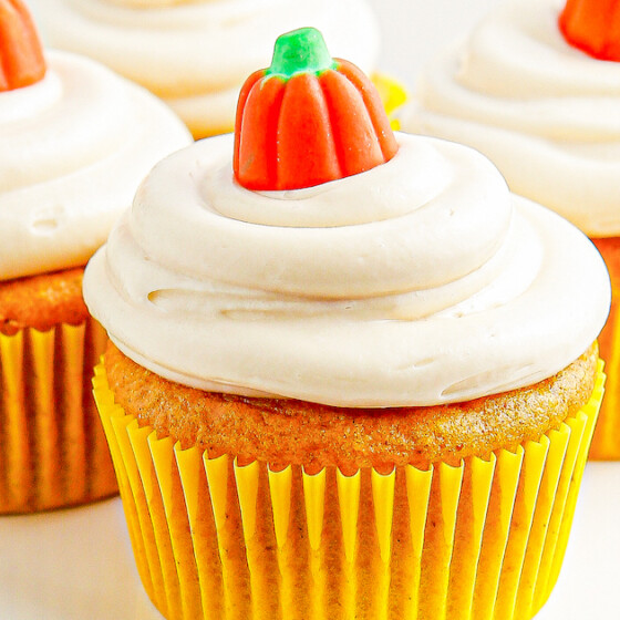 Cupcakes in yellow liners topped with candy pumpkins.