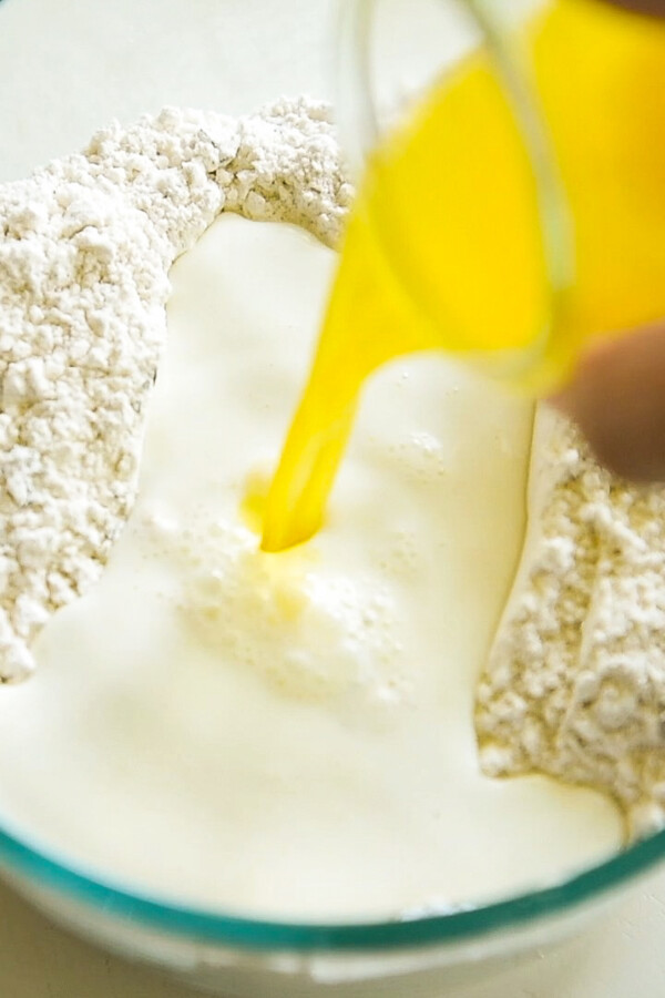 Melted butter being poured into a bowl with dry ingredients and milk.