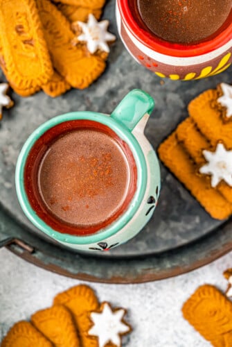 Overhead photo of Mexican hot chocolate in clay mugs. Lotus cookies on the side.