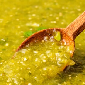 A bowl of salsa verde with a spoon in it.