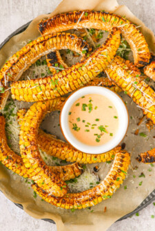 Overhead shot of baked corn with creamy dipping sauce.