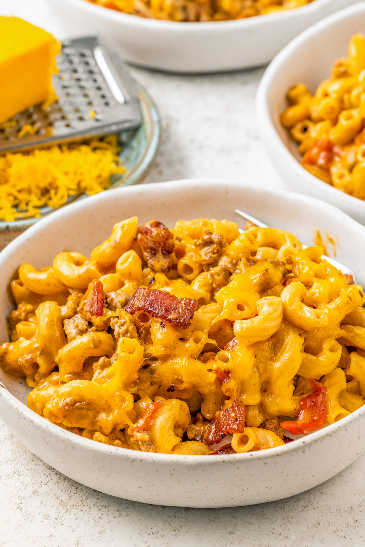 Bowls of macaroni with burger and tomatoes.