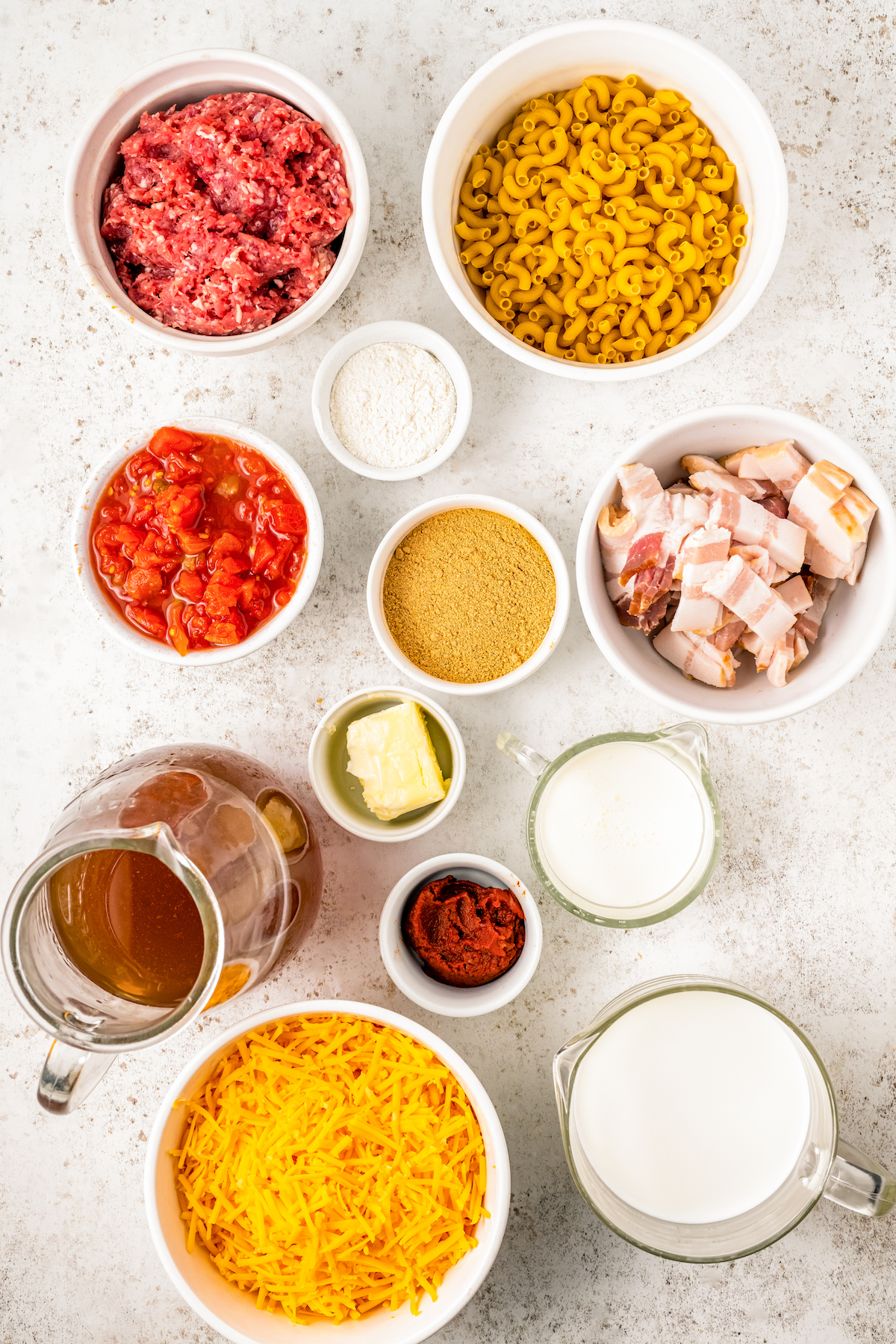 Ingredients for cheeseburger macaroni, arranged on a table.