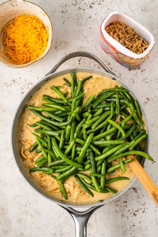 Mixing blanched green beans into cheese sauce.