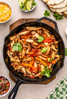 A skillet of chicken fajitas with onions and peppers.