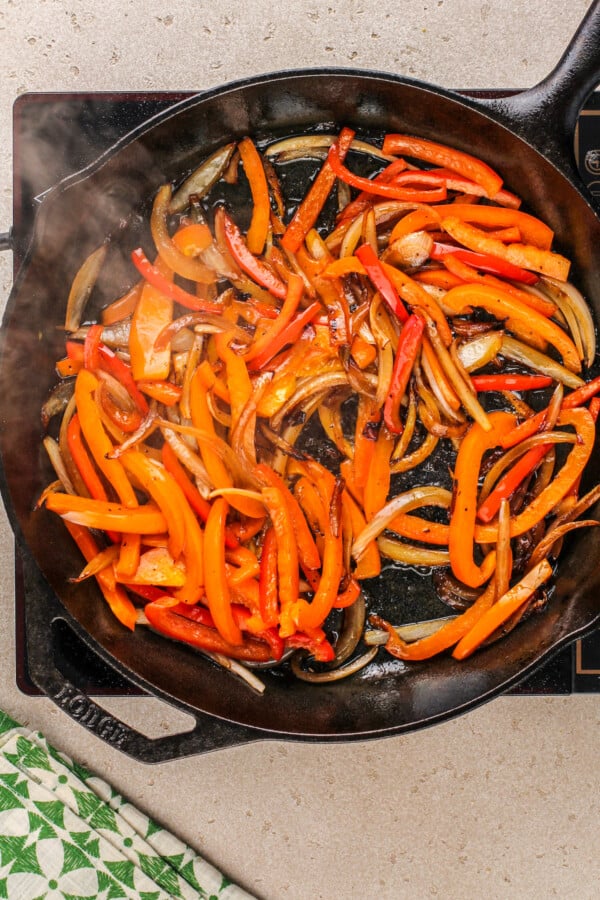Cooking peppers and onions in a skillet.