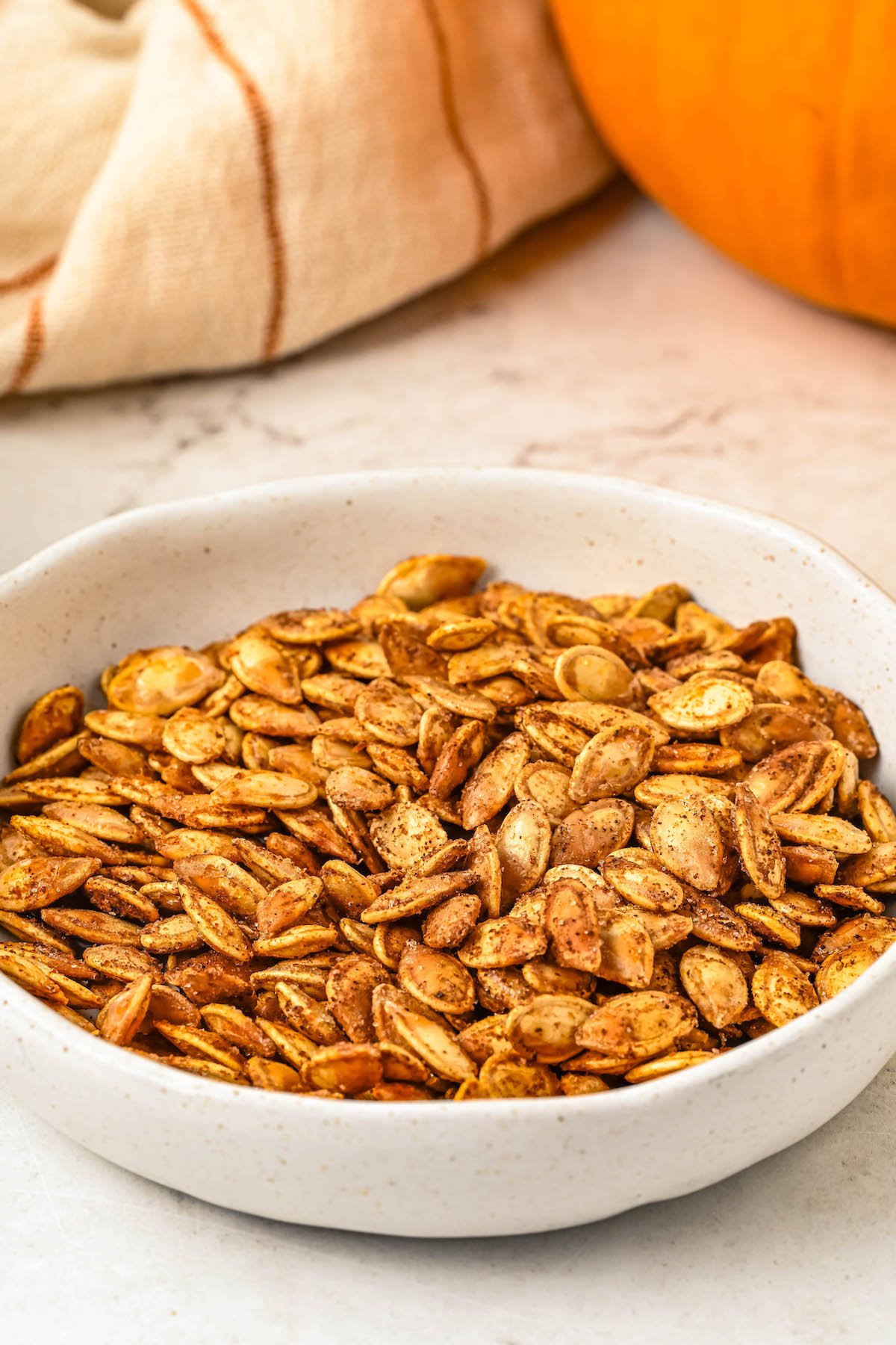 Baked pumpkin seeds in a white dish.