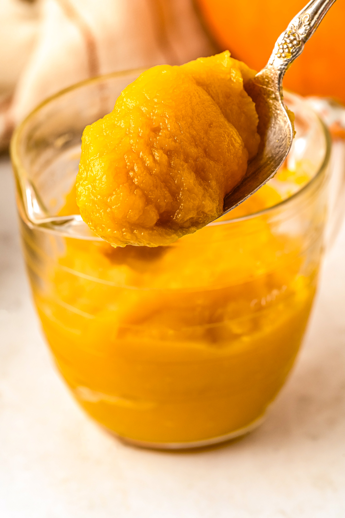 Lifting a spoon of pumpkin puree from a container.
