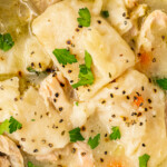 Landscape shot of chicken and dumplings garnished with cracked black pepper.