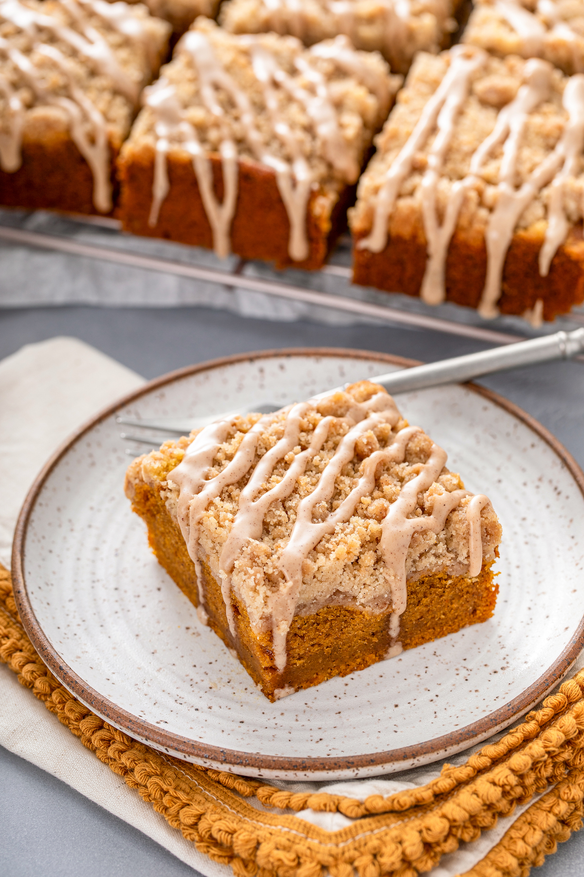 A serving of coffee cake on a plate, with more squares in the background.
