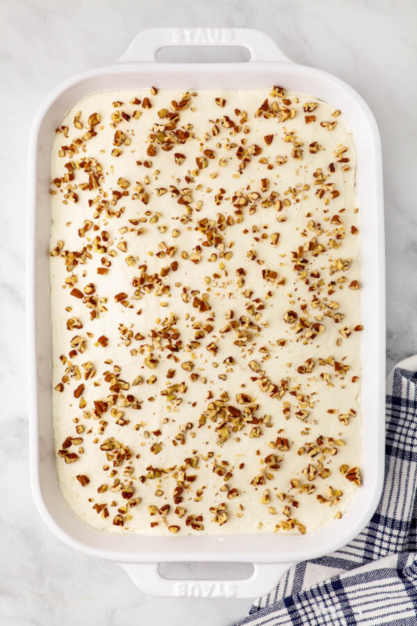 Chopped nuts sprinkled over a no-bake dessert in a baking dish.
