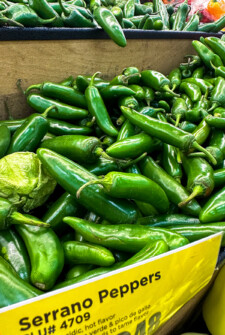 Serrano peppers in a bin with a label at the store.