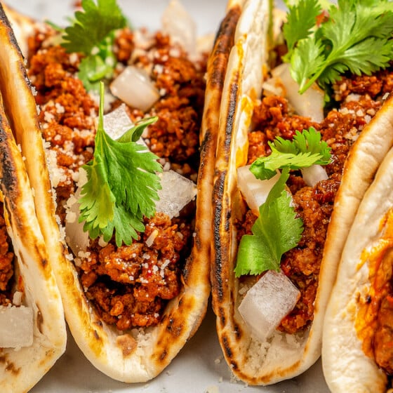 Four tacos stuffed with taco meat, onion, cilantro and crumbled Mexican cheese.