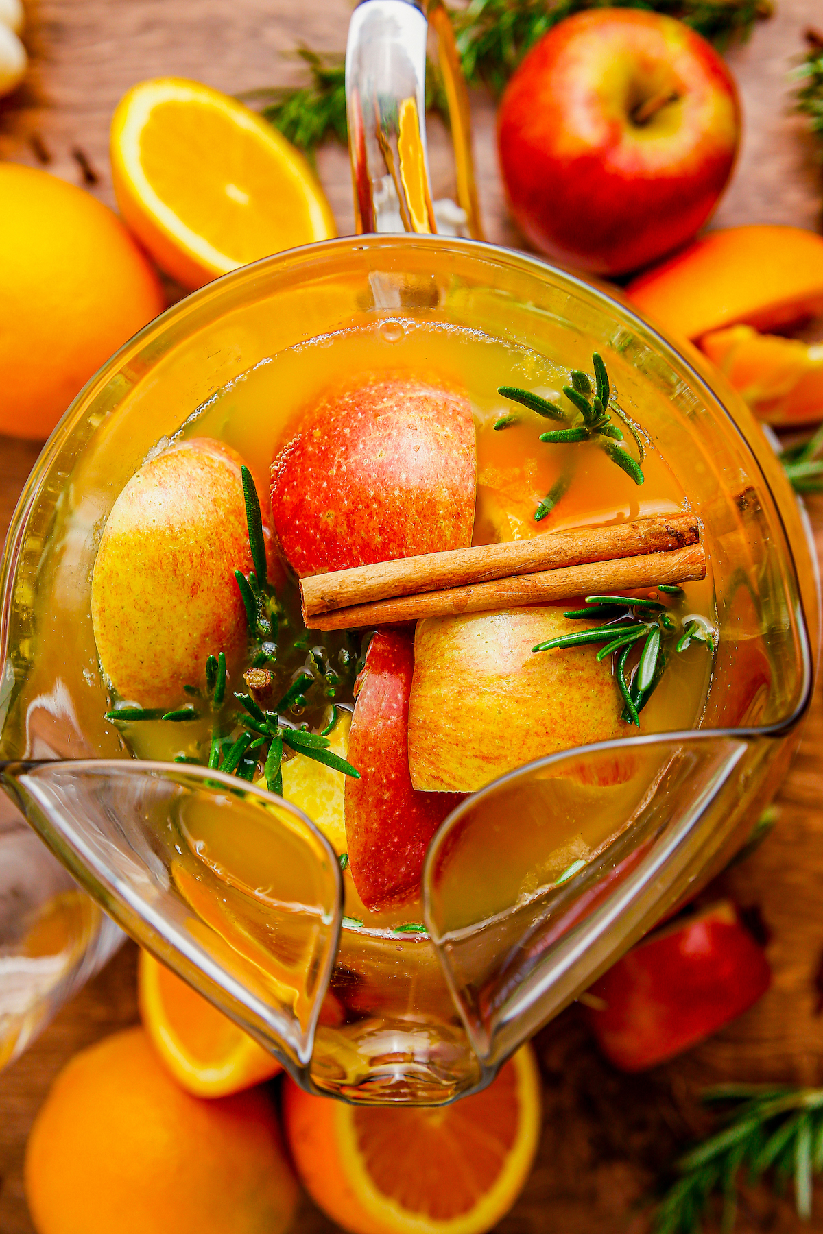 Overhead shot of a pitcher of punch with fruit and cinnamon sticks.