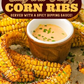 Baked corn ribs on a tray with a bowl of spicy sauce.