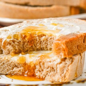 Honey Wheat Bread sliced into pieces on a plate and topped with butter and honey.