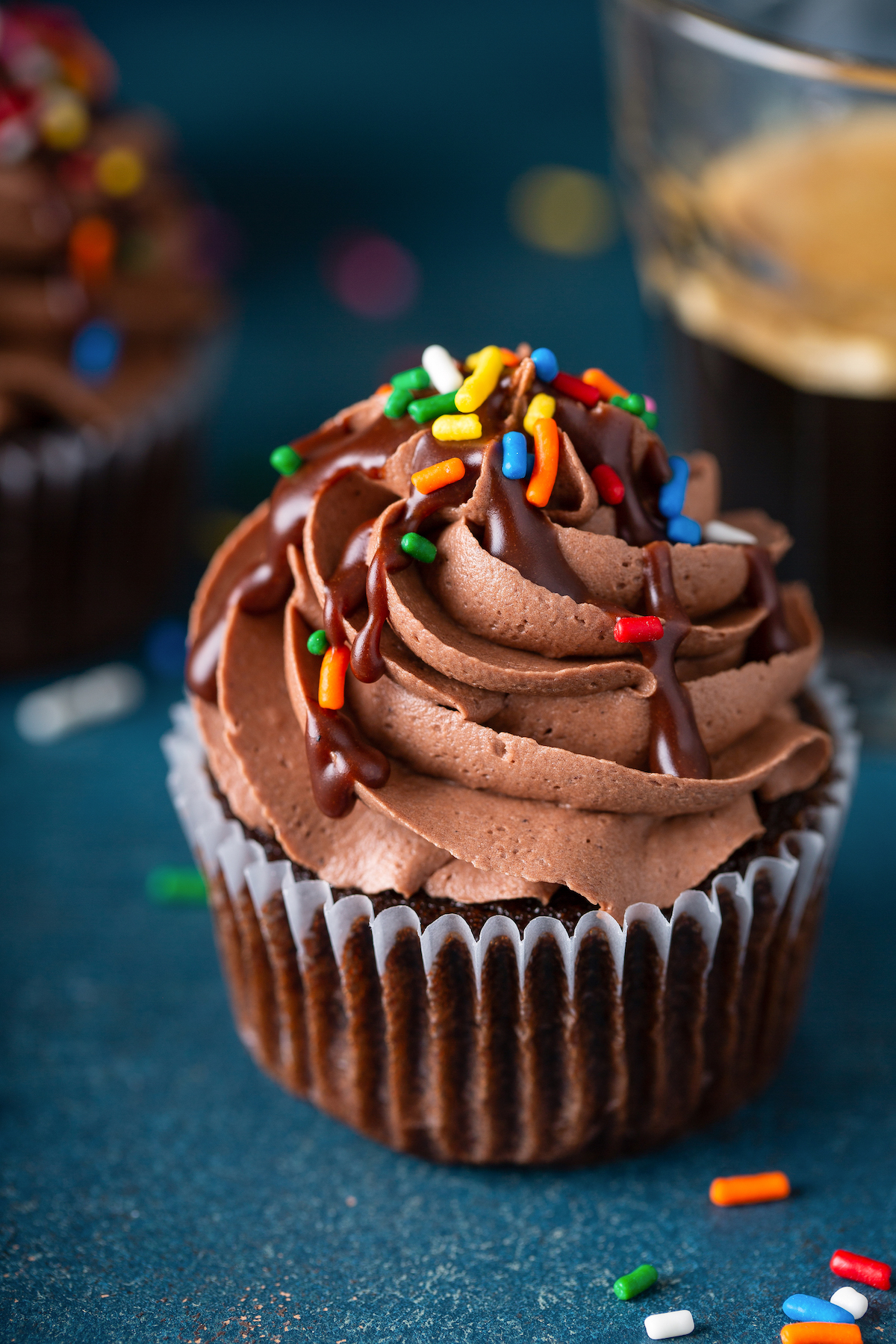 Homemade chocolate cupcakes on a dark blue background, with rainbow sprinkles.