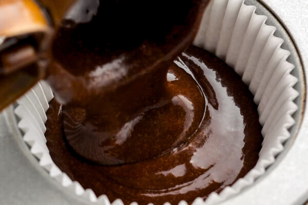 Filling a cupcake liner with chocolate batter.