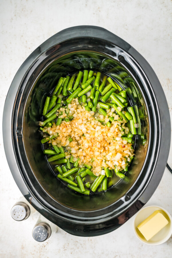 Fresh green beans in a crock pot with onions and garlic.