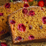 Cranberry pumpkin bread sliced with powdered sugar on top.