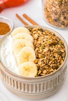 Granola in a small dish with yogurt and bananas.