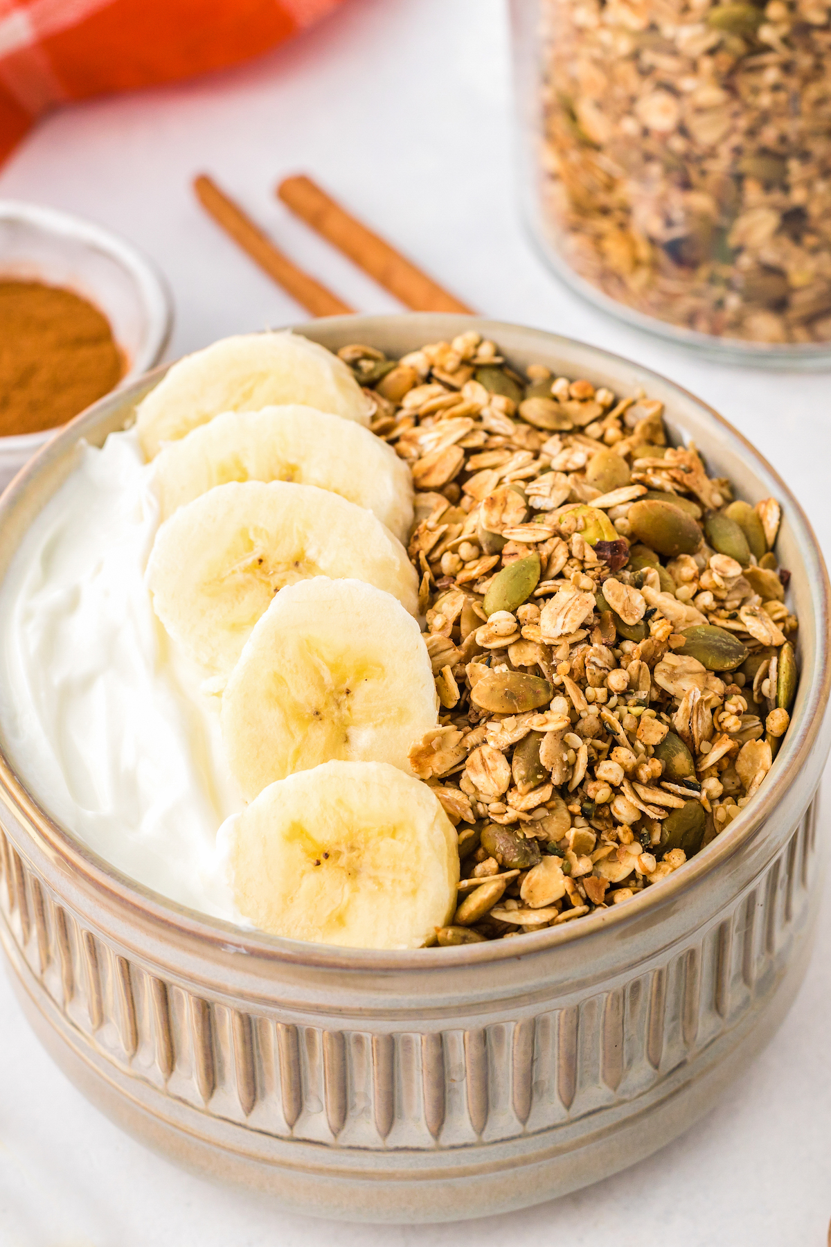Homemade granola in a small dish with yogurt and bananas.