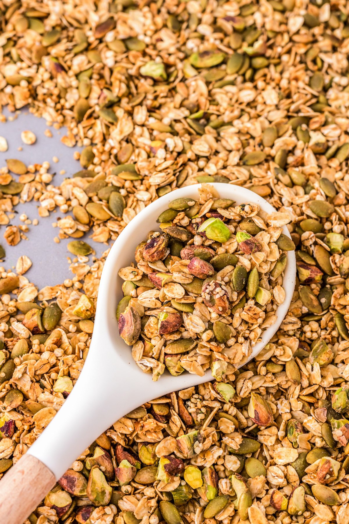 Close-up shot of a spoon of pumpkin spice granola resting in a pan of granola.