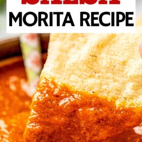 A tortilla chip scooping up salsa morita out of a bowl.