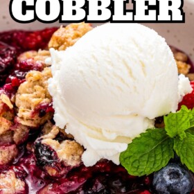 A serving of berry cobbler in a bowl with a scoop of ice cream on top.
