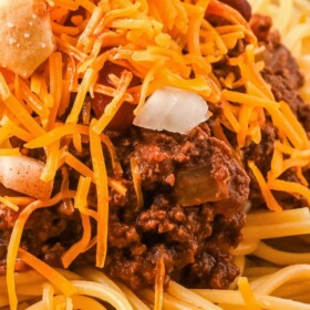 Cincinnati Chili over spaghetti with shredded cheese and onions on top.