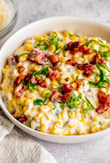 Bowl of creamy corn with fresh parsley and bacon.