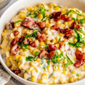 Bowl of creamy corn with fresh parsley and bacon.