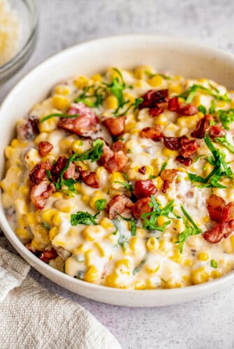 Bowl of creamy corn with fresh parsley and bacon.