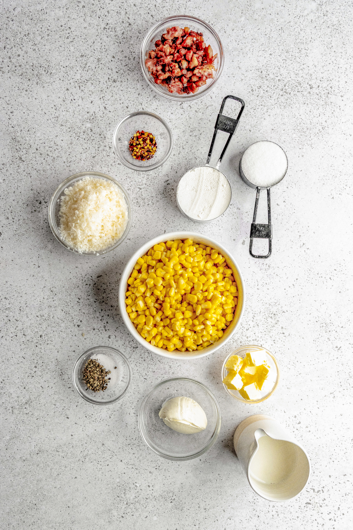 Ingredients for creamed corn recipe arranged in bowls on a countertop.