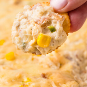 Hot crab dip is being scooped with a ritz cracker.