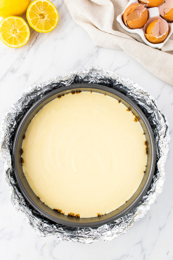 Lemon cheesecake batter is poured into a springform pan.