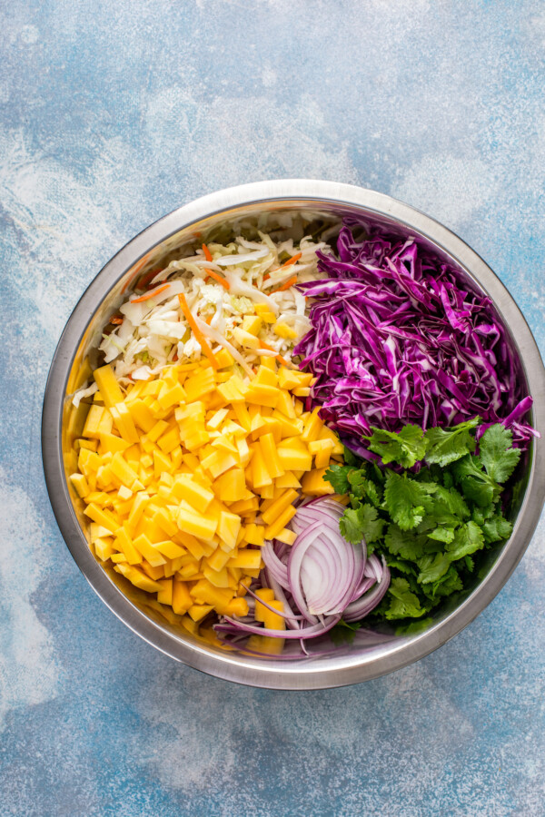 Ingredients for mango slaw are segmented in a stainless teel bowl.