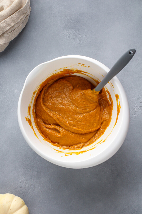 Pumpkin muffin batter in a bowl with a spatula.