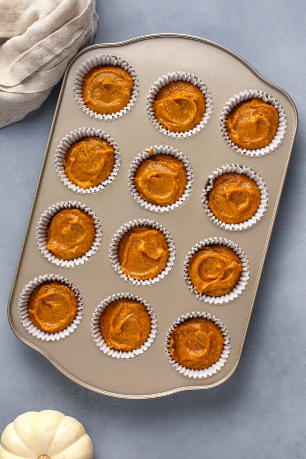 Pumpkin muffin batter in a muffin tin with liners.