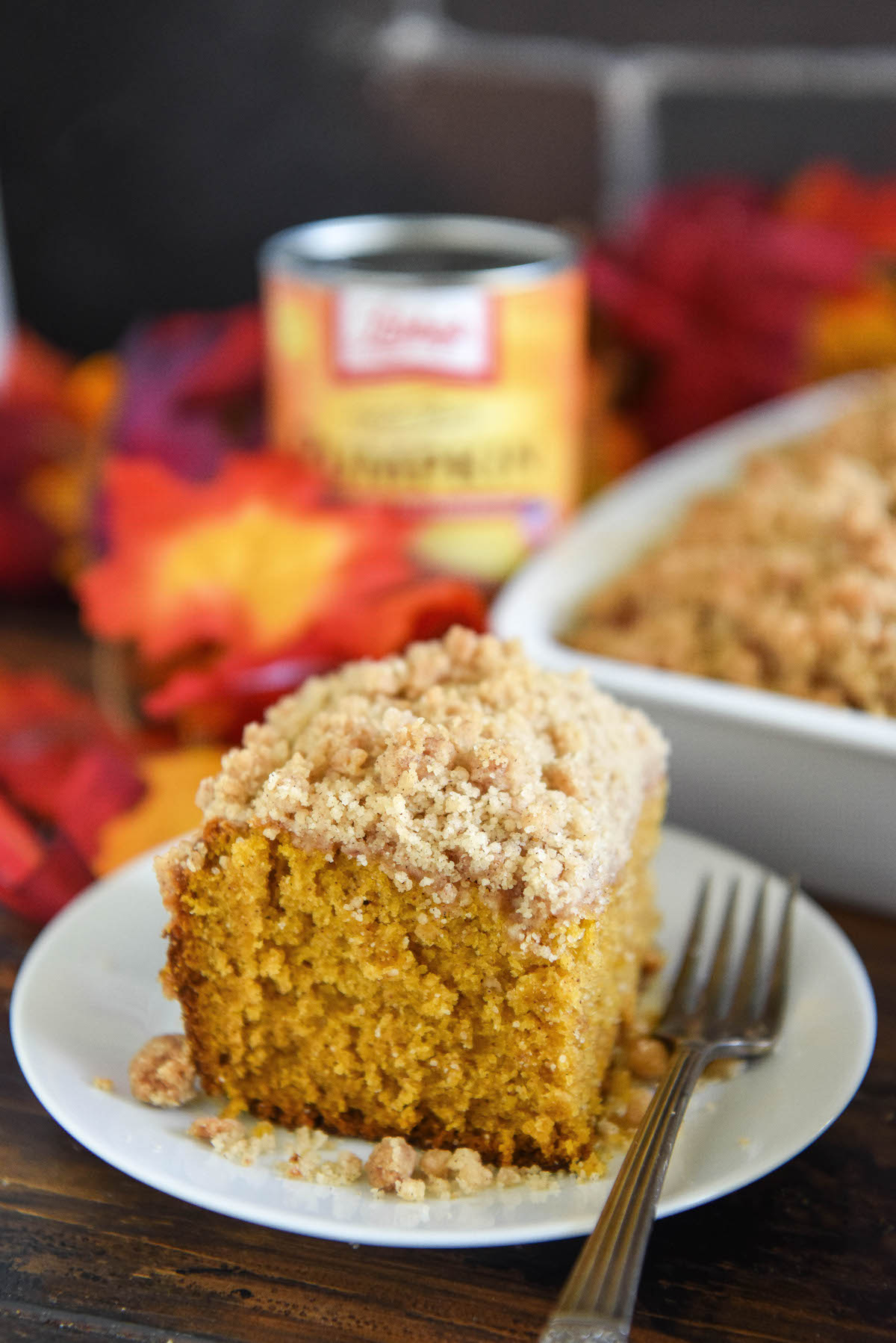 A slice of pumpkin cake with crumb topping on a plate with a fork.