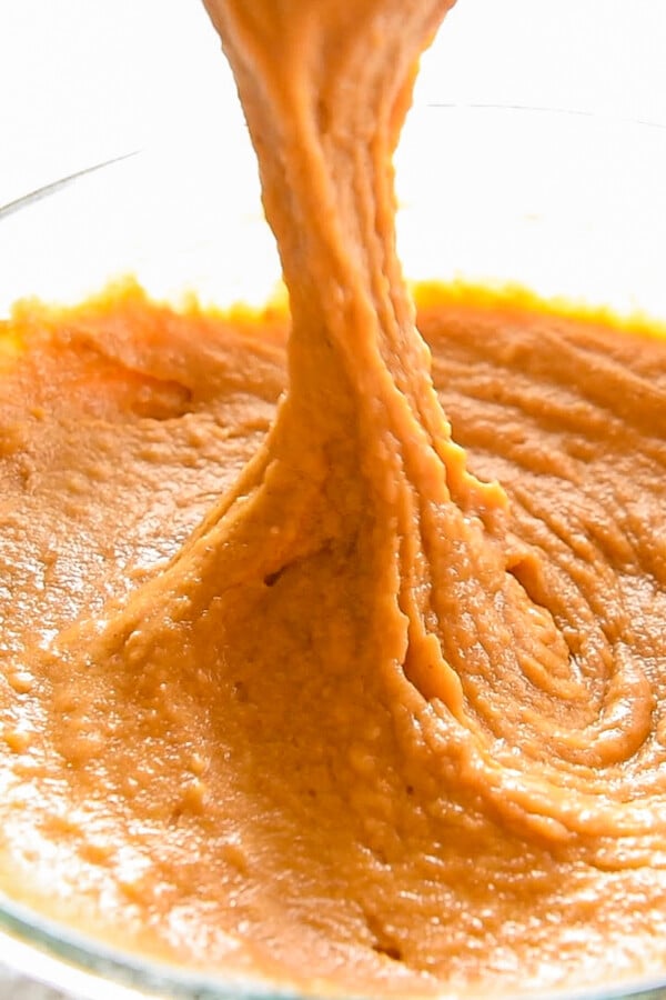 Pumpkin muffin batter in a bowl with a whisk stirring it.