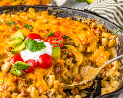 Taco mac and cheese in a skillet with a serving spoon.