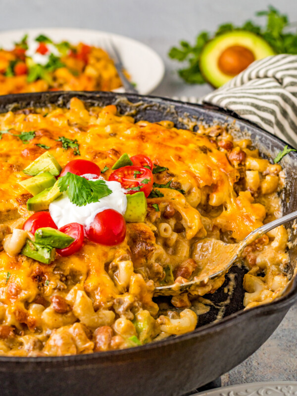 Taco mac and cheese in a skillet with a serving spoon.