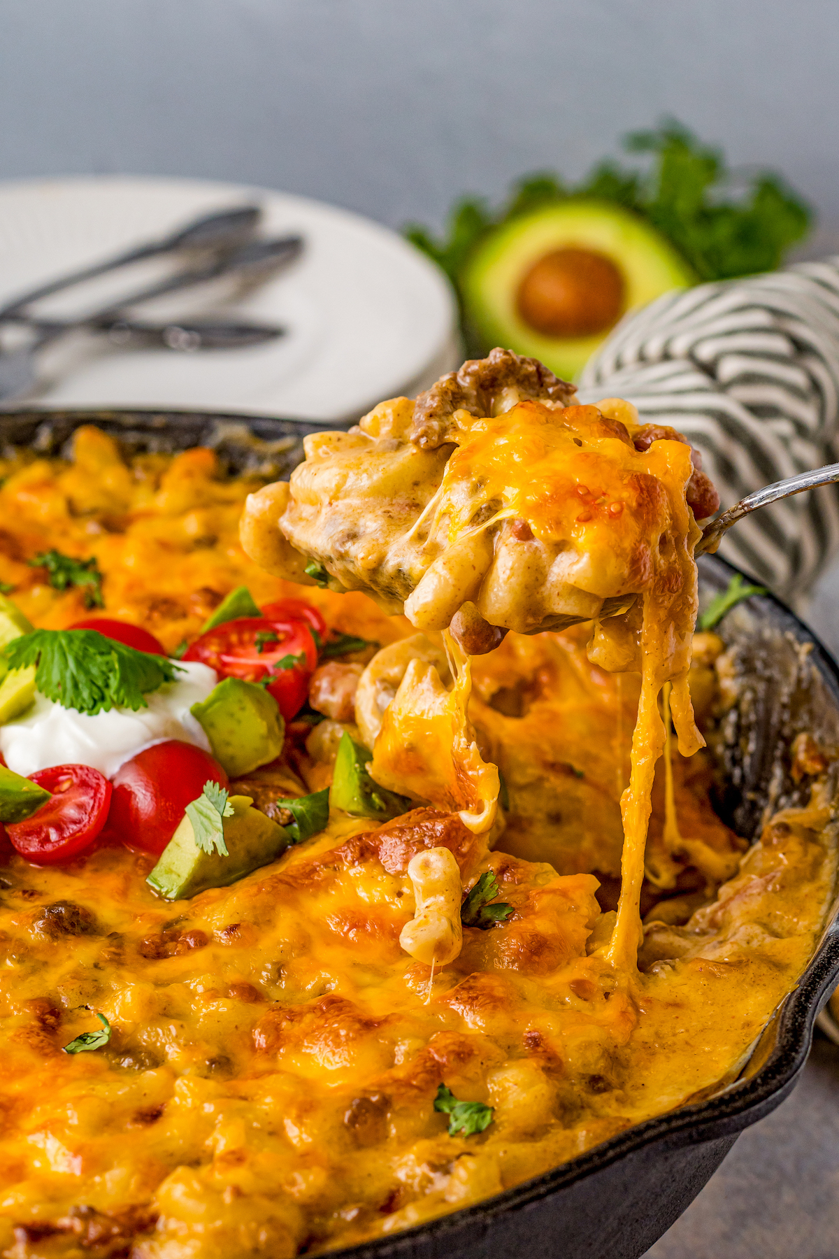 A spoonful of taco mac and cheese is lifted from a skillet.
