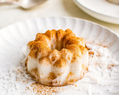 Tembleque on a plate with ground cinnamon and coconut flakes sprinkled on top.