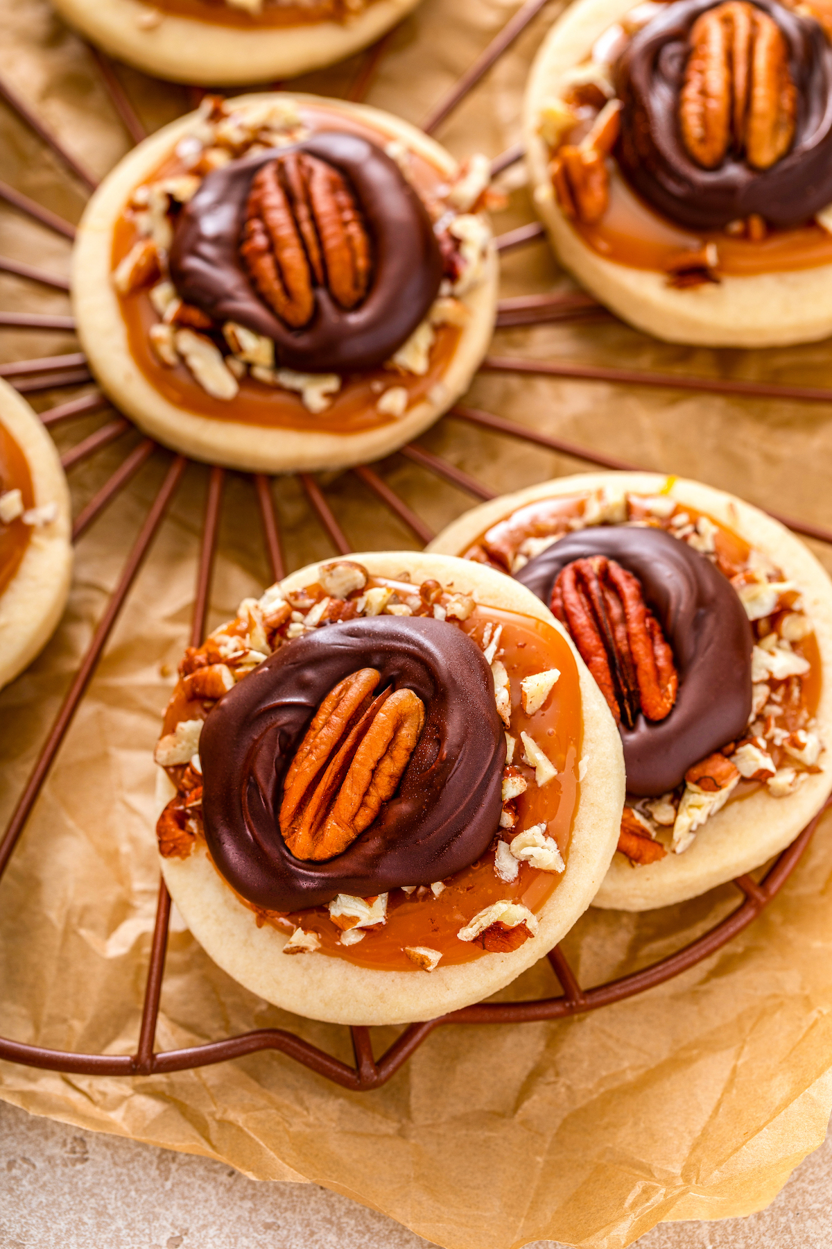 Turtle cookies with chocolate, caramel. and pecans cool on a rack.