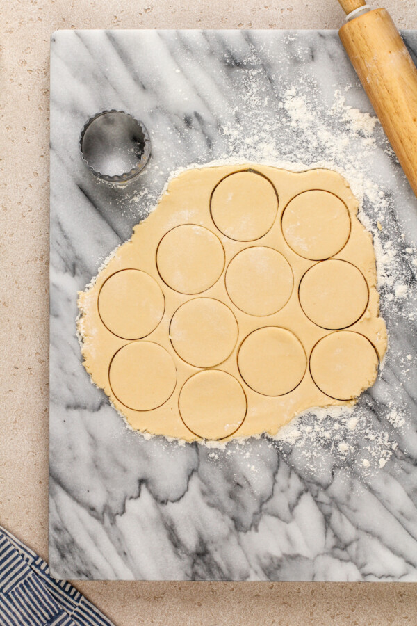 Sugar cookie dough is rolled out with circles cut into the dough.